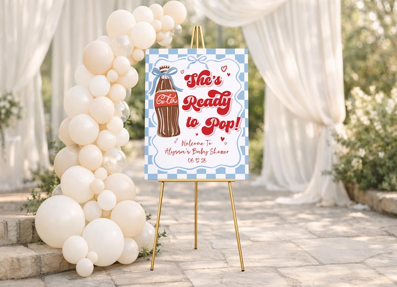 Puede incluir: Un letrero de bienvenida para baby shower sobre un caballete dorado. El letrero tiene un borde a cuadros azul y blanco y presenta una ilustraci&oacute;n de botella de cola y el texto "She's Ready to Pop!" con los detalles del baby shower.