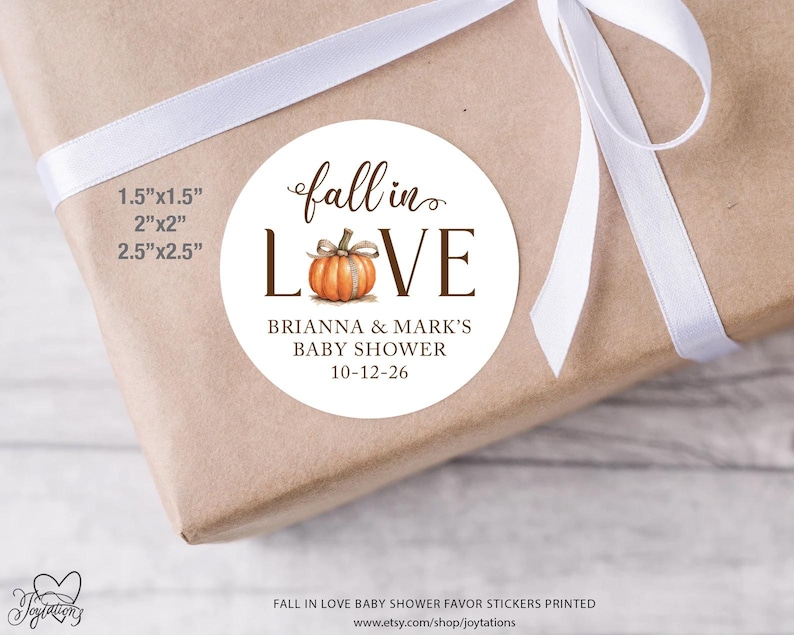 May include: A round white sticker featuring a watercolor orange pumpkin replacing the letter O in the text fall in LOVE. Below the pumpkin, the text reads BRIANNA & MARK'S BABY SHOWER 10-12-26. Available sizes listed are 1.5"x1.5", 2"x2", and 2.5"x2.5".