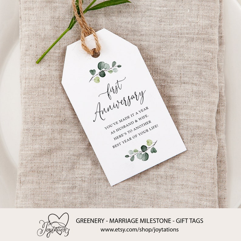 May include: White gift tag with green foliage and the text "first Anniversary" and "You've made it a year as husband & wife. Here's to another best year of your life!"