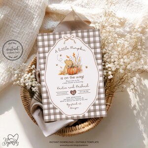 May include: A rectangular baby shower invitation card featuring a brown and white gingham border and a central illustration of a bear with a pumpkin. The text reads A little Pumpkin is on the way, honouring Kristie and Michael on October 12.