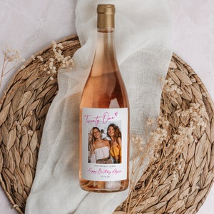 May include: A pink wine bottle with a custom label that says "Twenty One" and "Happy Birthday Alyss" with a photo of two women. The label also includes the date "10.14.22".