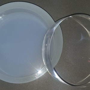 Peut inclure: Un couvercle en verre transparent et un moule en silicone blanc pour la création d'objets en résine. Le moule est rond et possède un bord surélevé.