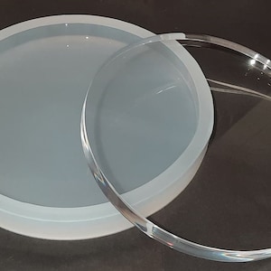 Könnte beinhalten: Ein rundes, transparentes Glastablett mit einer weißen Silikonform darauf. Die Form ist etwas kleiner als das Tablett.