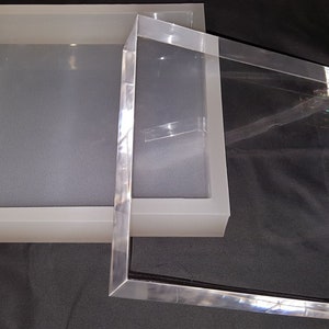 May include: A clear acrylic box with a frosted white lid. The box is square and has a simple design.