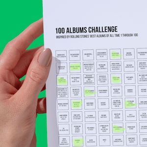 May include: A white sheet of paper with a black grid containing a list of 100 albums, titled "100 Albums Challenge" and "Inspired by Rolling Stones' Best Albums of All Time 1 Through 100". Some of the album titles are highlighted in green.