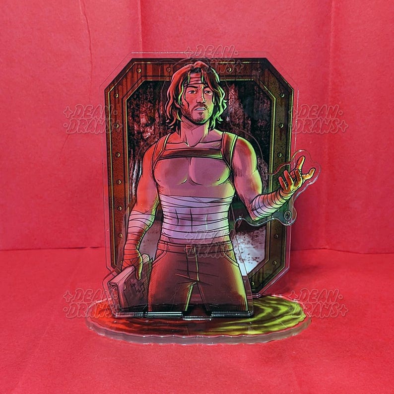 May include: A clear acrylic figure of a man with long hair, wearing a tank top, bandages, and brown pants. The figure is set against a background of a wooden door and a red surface. The base of the figure is a green and yellow liquid.