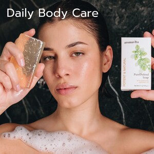 A woman in the shower holds Aromavita PureDefend Soap and a translucent soap bar, symbolizing daily body care. The image highlights the soap’s potent, natural ingredients, designed to cleanse, moisturize, and nourish skin for a refreshed, smooth feel