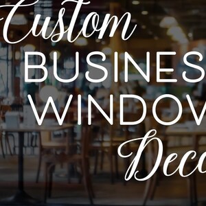 May include: Custom Business Window Decal, a white vinyl sticker with a cursive font, displayed on a glass storefront window. The decal is visible through the window, which shows a blurred image of a restaurant interior.