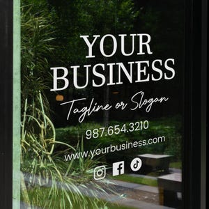 May include: A window with white text that reads "YOUR BUSINESS" above "Tagline or Slogan". Below is a phone number and website address. Social media icons for Instagram, Facebook, and TikTok are at the bottom.