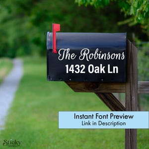 May include: Black mailbox with the name "The Robinsons" and address "1432 Oak Ln" in white script. The mailbox has a red flag and is mounted on a wooden post. Text at the bottom reads "Instant Font Preview Link in Description".