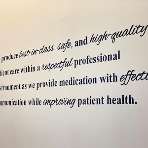May include: A wall decal with the text "OUR MISSION" in a vertical column on the left. The main text describes a commitment to patient care, medication, and communication. The decal has a white background.