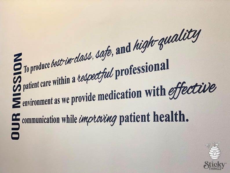 May include: A wall decal with the text "OUR MISSION" in a vertical column on the left. The main text describes a commitment to patient care, medication, and communication. The decal has a white background.