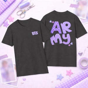 Pode incluir: Duas camisetas pretas. Uma tem o texto "BTS" em roxo, a outra "ARMY" em roxo com um padrão xadrez e bolinhas. As camisetas são de manga curta.