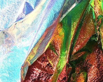 May include: Close-up of iridescent fabric in blue, green, and red colors. The fabric is crumpled and folded, creating a textured and abstract pattern.
