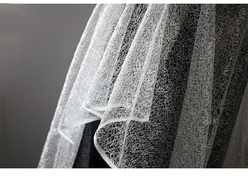 Pu&ograve; includere: Tessuto di tulle bianco con un delicato motivo testurizzato. Il tessuto &egrave; morbido e trasparente, con un leggero bagliore iridescente.