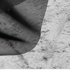 May include: Black sheer fabric with a fine mesh texture. The fabric is draped over a textured surface.