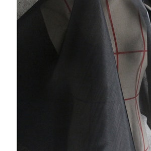 May include: Black sheer fabric with a slightly textured surface. The fabric is draped over a dress form.