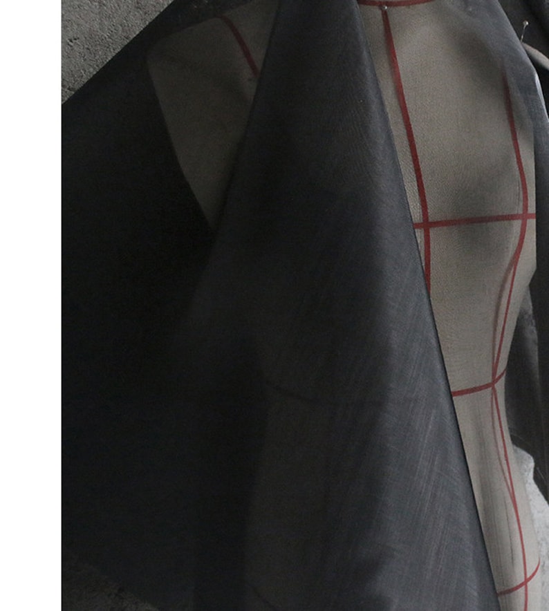 May include: Black sheer fabric with a slightly textured surface. The fabric is draped over a dress form.