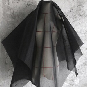 May include: Black sheer fabric draped over a dress form. The fabric is lightweight and translucent, with a soft, flowing texture.