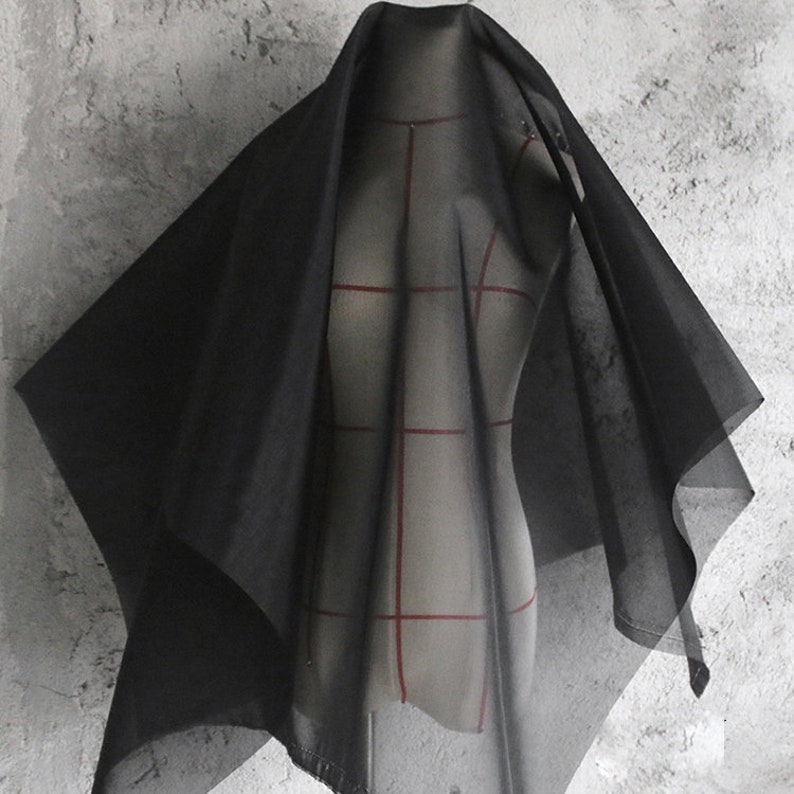 May include: Black sheer fabric draped over a dress form. The fabric is lightweight and translucent, with a soft, flowing texture.
