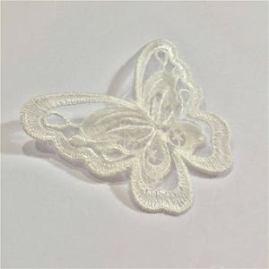 May include: White lace butterfly applique with delicate details. This intricate design is perfect for adding a touch of elegance to crafts and sewing projects.