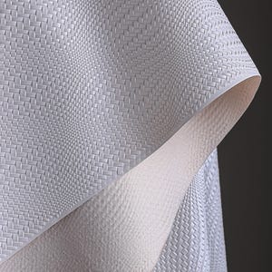 May include: Close-up of a textured, off-white material with a woven pattern. The material is folded, revealing a contrasting, smooth, light-coloured underside. The overall effect is a play of textures and tones.