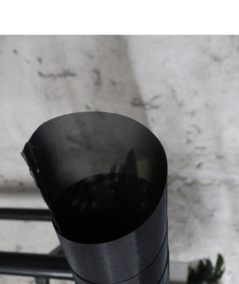 May include: A black mesh fabric rolled up into a cylinder shape. The fabric has a fine weave and is slightly translucent.