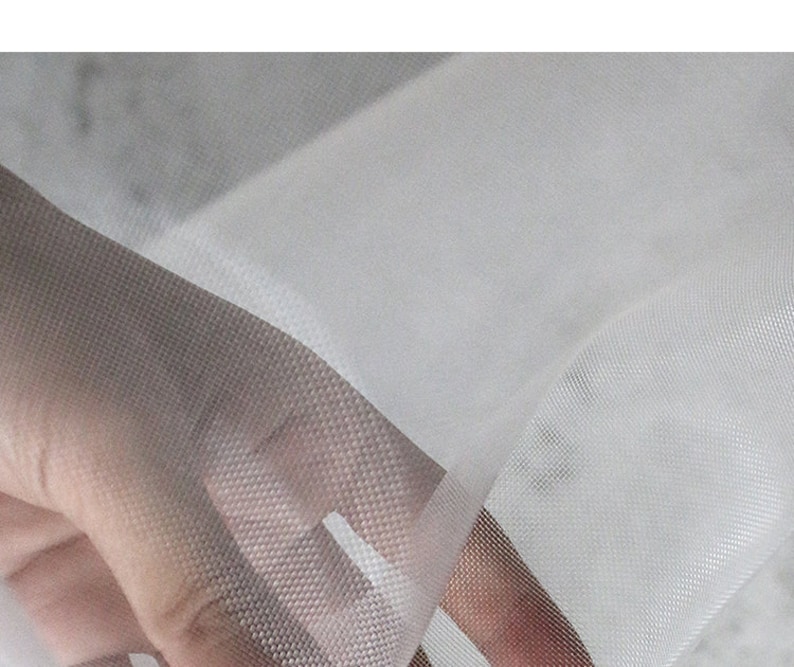 May include: White sheer mesh fabric with a fine, even weave. The fabric is soft and delicate, with a slightly translucent appearance.