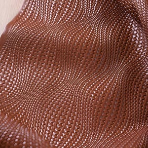 May include: Close-up of a brown woven material with a textured surface. The material is folded and curved, creating a wave-like pattern. The weave is tight and detailed, with a slight sheen.