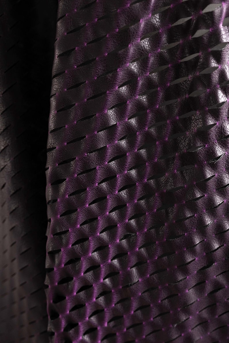 Puede incluir: Un material de color morado oscuro con una superficie texturizada similar al cuero, que presenta un patr&oacute;n repetitivo de cortes horizontales. Los bordes de estos cortes revelan un tono morado brillante, creando una apariencia dimensional.