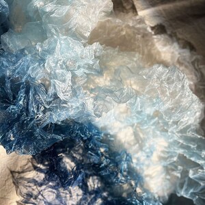 Puede incluir: Primer plano de un degradado de tela azul, con el tono m&aacute;s claro en la parte superior y el m&aacute;s oscuro en la parte inferior. La tela est&aacute; arrugada y tiene una textura delicada, casi transl&uacute;cida.