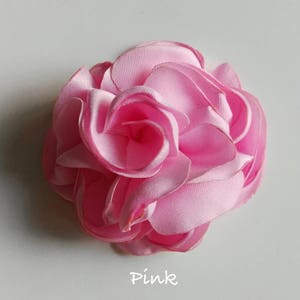 May include: A pink fabric rose flower with multiple layers of petals.