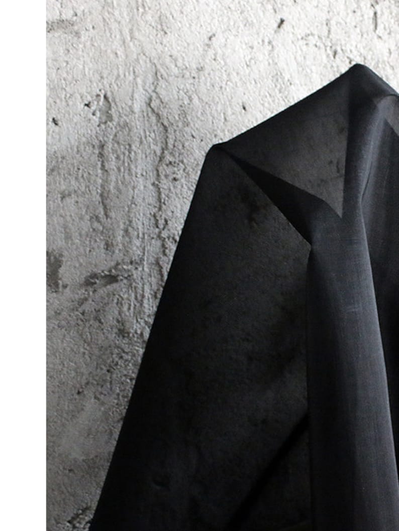 May include: Black sheer fabric with a smooth texture. The fabric is draped over a textured surface.