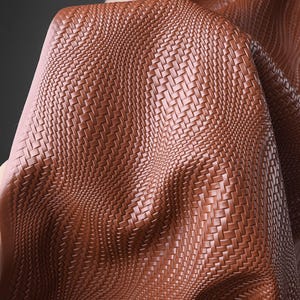 May include: A close-up shot of brown leather fabric with a basketweave design. The material is folded, revealing its texture and depth. The colour is a warm, reddish-brown, similar to tan.