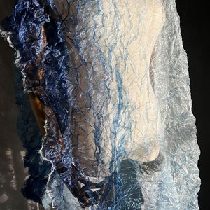 Puede incluir: Una bufanda transparente de color azul y blanco degradado con textura arrugada. La bufanda est&aacute; drapeada sobre un maniqu&iacute;.