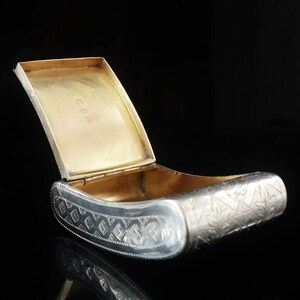 May include: A silver and gold hinged box with an engraved design. The box is open and the inside is lined with gold.