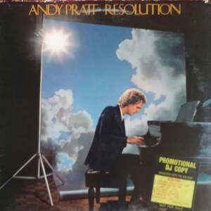 May include: A vinyl record album cover featuring a man playing a piano in front of a cloudy sky backdrop. The album title "Andy Pratt Resolution" is printed in gold lettering at the top of the cover. A promotional DJ copy sticker is attached to the bottom right corner of the cover.