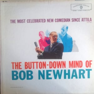 May include: Album cover for "The Button-Down Mind of Bob Newhart." The image features a portrait of Bob Newhart holding a microphone, with a background of colorful images. Text includes "The Most Celebrated New Comedian Since Attila."