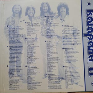 May include: An open vinyl record album with four men in a light blue and white design. The album cover has the text "Kalapana II" in blue. The album's interior includes song lyrics and the text "Side One" and "Side Two".