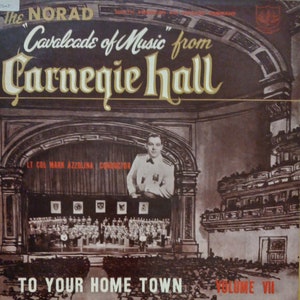May include: A vintage record album cover featuring a black and white illustration of a stage with an orchestra and a conductor. The album title is "Cavalcade of Music from Carnegie Hall" with the text "To Your Hometown Volume VII" at the bottom.