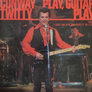 May include: Album cover featuring Conway Twitty, with the text "CONWAY TWITTY PLAY, GUITAR PLAY." Twitty is playing a black electric guitar, wearing a red shirt and black vest. The text "I CAN'T BELIEVE SHE GIVES IT ALL TO" is also visible.