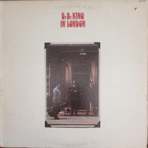 May include: Album cover for B.B. King's "In London." The album cover features a photograph of B.B. King and three police officers in front of a building. The album title is in red block letters at the top.