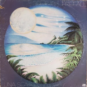 May include: A vintage vinyl record album cover featuring a blue and white illustration of a tropical island scene with a full moon, palm trees, and a beach. The album title "Luna Sea" is printed in white at the bottom of the cover. The band name "Firefall" is printed in white at the top of the cover.