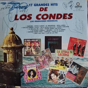 May include: Vintage vinyl record album cover titled "17 Grandes Hits De Los Condes." The cover features multiple album covers, signatures, and a drawing. The main cover is light blue with red text and a picture of a stone structure.