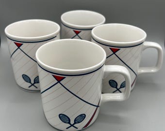 May include: Set of four white ceramic mugs with a blue and red geometric design featuring tennis rackets.