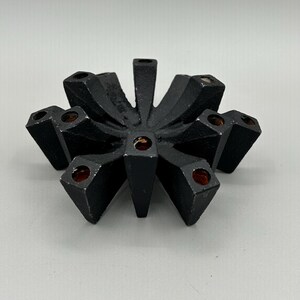 May include: Black cast iron candle holder with a starburst design and eight candle slots.