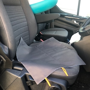 Puede incluir: Una funda de asiento negra con lazos amarillos se coloca sobre un asiento de coche gris. Una tabla de paddle surf inflable blanca y turquesa descansa contra el asiento. Se ve el interior de un veh&iacute;culo.