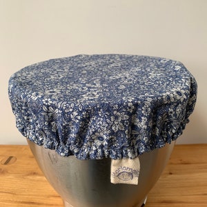 May include: A blue and white floral patterned fabric bowl cover with a white label that says "bloom"