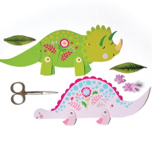 May include: Two paper dinosaur puppets with floral designs. The green dinosaur has three horns and the pink dinosaur has a spiky back. Both dinosaurs have movable legs and tails.