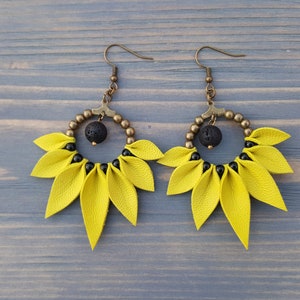 May include: A pair of yellow leather earrings with black beads and a black lava rock bead in the center of each earring.